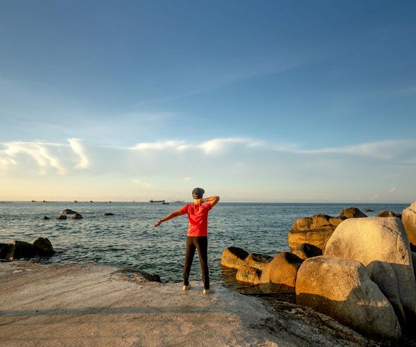 Silhouette of a man stretching against a sunrise, symbolizing energy and well-being.